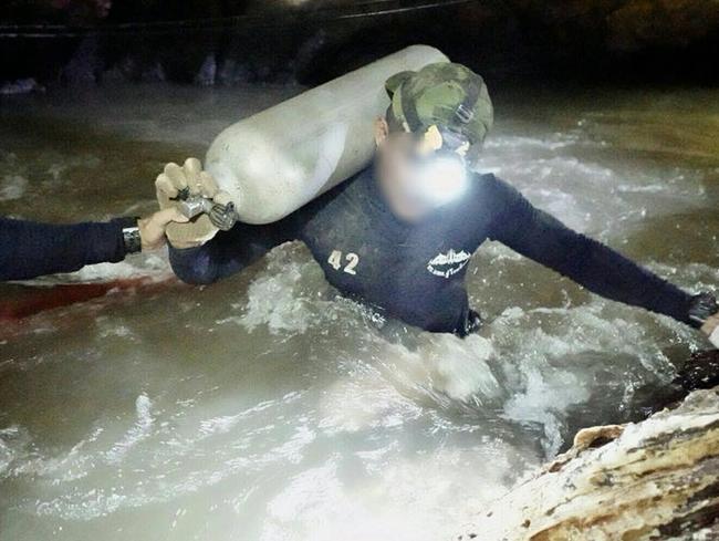A Royal Thai Navy SEAL carries an oxygen tank through the cramped passages of Tham Luang cave.