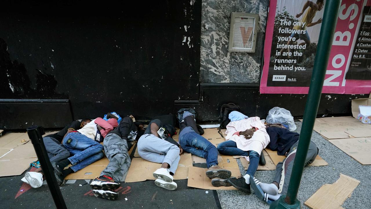 Migrants sleeping on the floor waiting to be processed at the Roosevelt Hotel. (Photo by TIMOTHY A. CLARY / AFP)