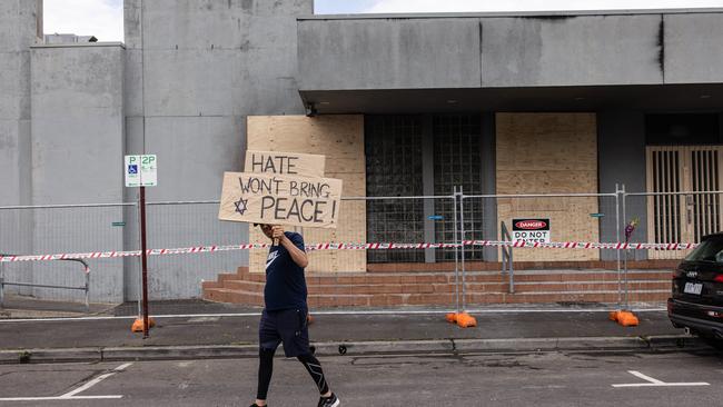 A man holds a placard in front of the synagogue that was attacked on December 6. Picture: NewsWire / Diego Fedele