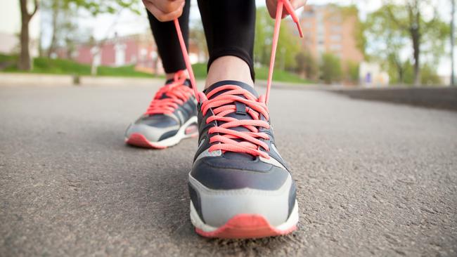 Sporty woman tying shoelace on running shoes before practice. Female athlete preparing for jogging outdoors. Runner getting ready for training. Sport active lifestyle concept. Close-upGeneric, istock