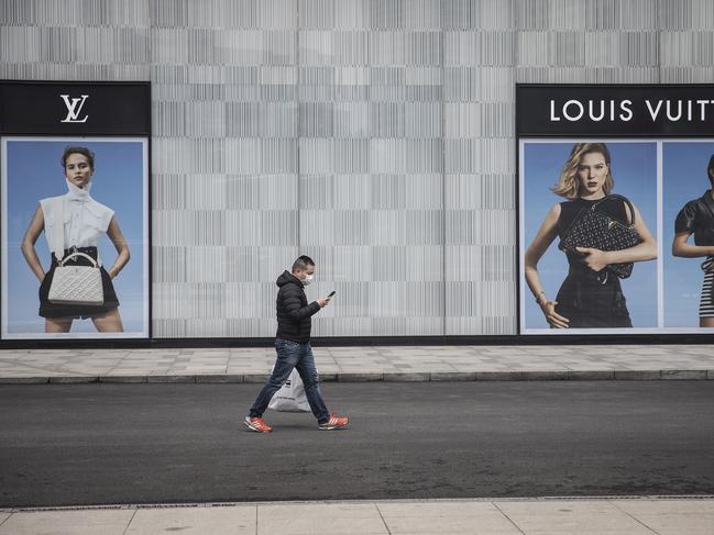 A man wearing a face mask passes a Louis Vuitton store outside Wuhan international plaza in Hubei Province, China. Picture: Getty