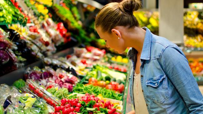 A young blond woman in the supermarket is looking for some fruits generic istock