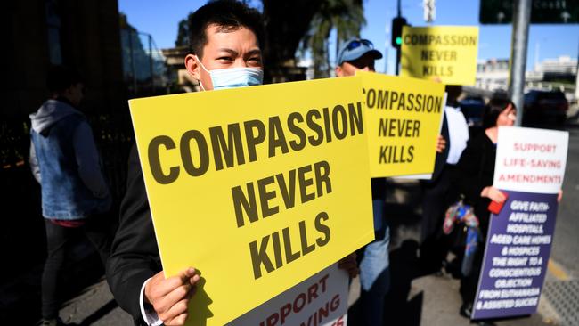 Protesters hold signs outside Parliament House ahead of the vote on Queensland’s ng proposed voluntary assisted dying laws. Picture: NCA NewsWire/Dan Peled