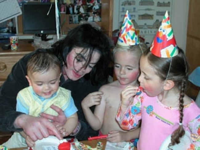 Prince and Paris wear paper hats as their father Michael Jackson cuddles the youngest child 'Blanket'