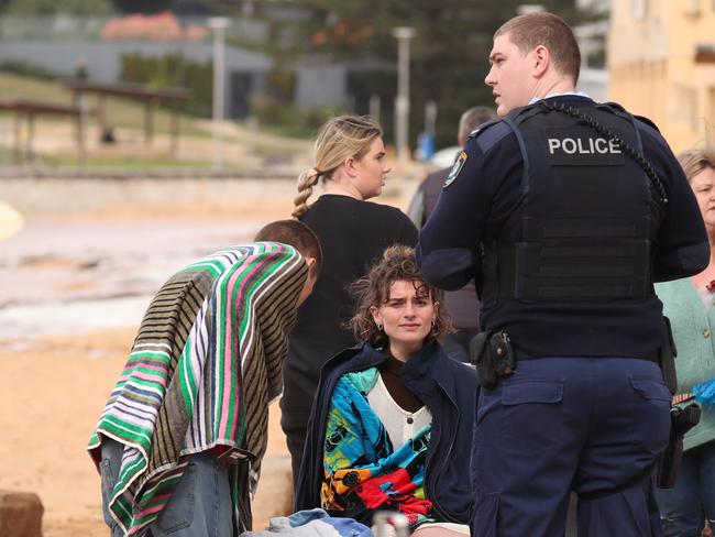 The unidentified man and woman, with towels around them, who jumped into the surf to rescue the unresponsive surfer, talk to police. Picture: John Grainger