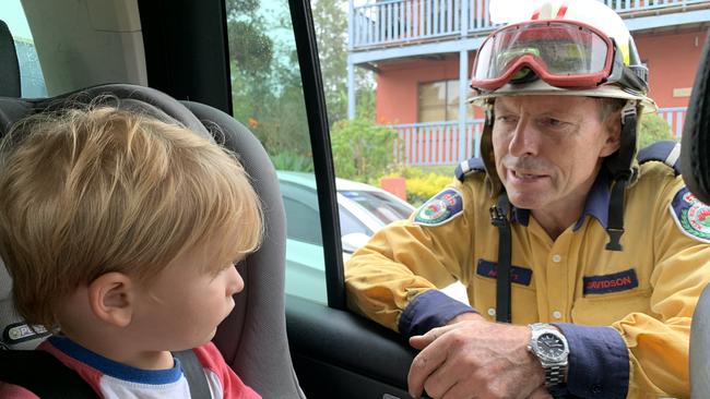 Former prime minister Tony Abbott, talks to Taje Lawson, 3, from North Narrabeen after his family bumped into the volunteer rural firefighter at Milton while he was on duty fighting bush fires on the NSW south coast. Picture: Sarah Lawson