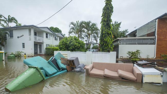 Damaged furniture and appliances strewn in the flooded streets of Hermit Park as heavy rain continues to fall in Townsville. Picture: Lachie Millard