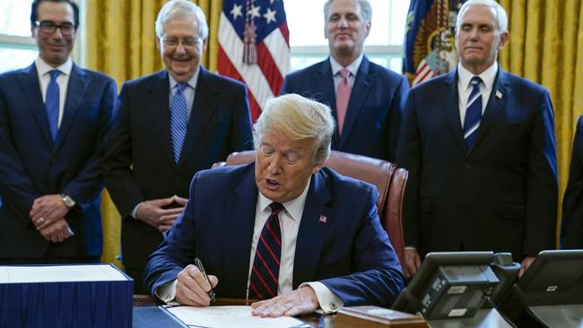 President Donald Trump signs the coronavirus stimulus relief package in the Oval Office. Picture: AP