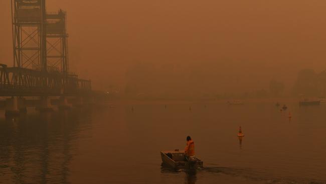 A Rural Fire Service volunteer sails a boat as smoke haze settles over the town of Batemans Bay, New South Wales on Wednesday morning. Picture: Sam Mooy/The Australian