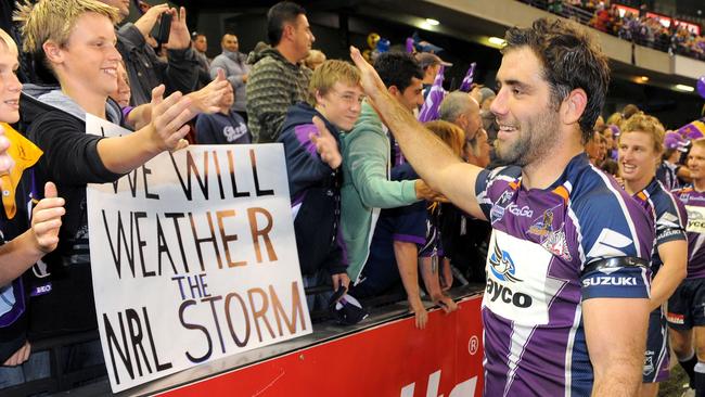 Melbourne Storm captain Cameron Smith (R) high-fives fans after they defeated the New Zealand Warriors in their first match since been found guilty of breaching the salary cap. Picture: AFP Photo/William West