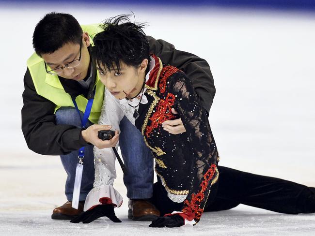 In this Saturday, Nov. 8, 2014 photo, Yuzuru Hanyu, right, of Japan is helped by a medical team member after he clashed with Yan Han of China during a practice prior to their free program performance at the Cup of China in Shanghai, China. (AP Photo/Kyodo News) JAPAN OUT, MANDATORY CREDIT