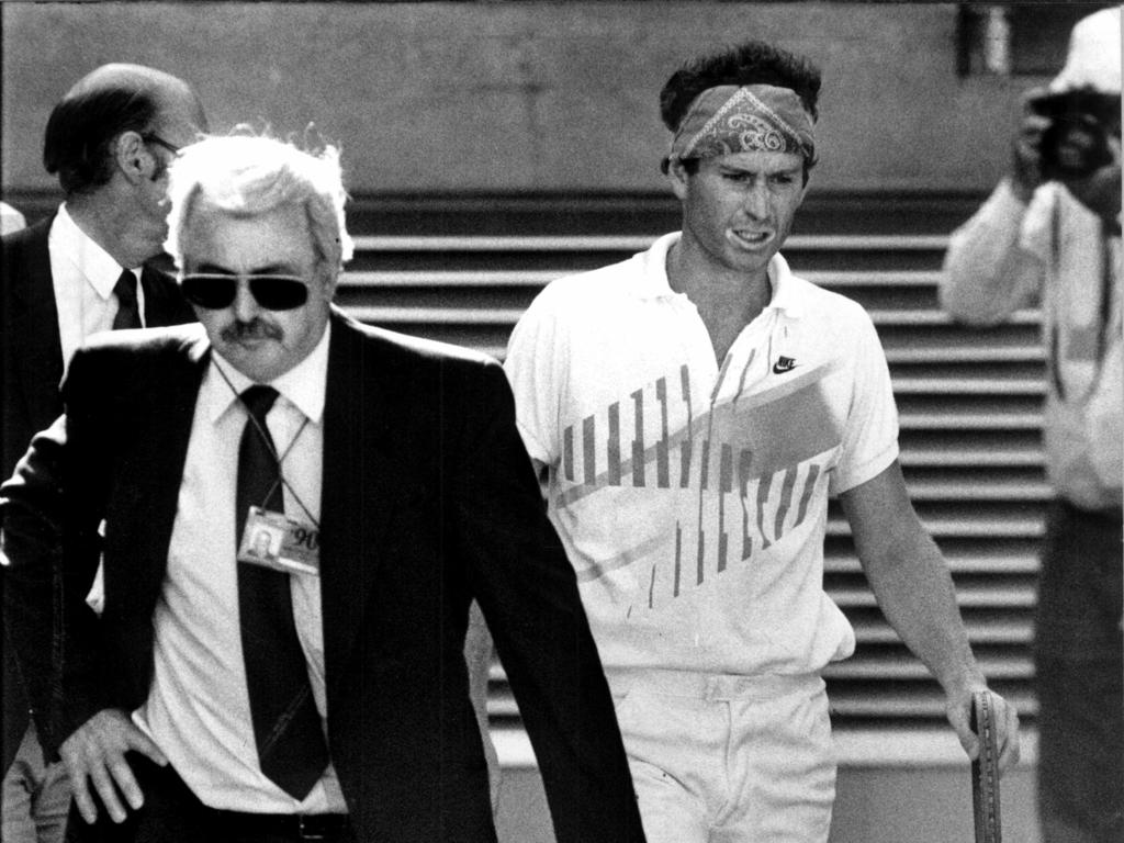 John McEnroe (right) is escorted off Centre Court during the 1990 Australian Open.