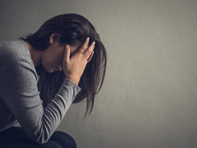 Depressed woman sitting on a chair in dark room at home. Lonly , sad, emotion concept.