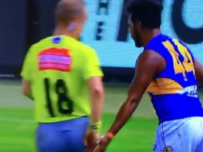 Willie Rioli taps umpire Ray Chamberlain on the backside.