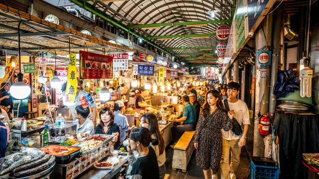 View of an alley of the Kwangjang market at night, with people eating street food at stalls in Seoul, Korea. Picture: iStock