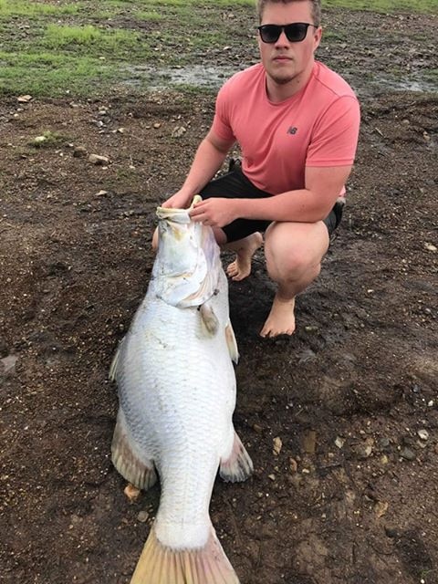 Jesse Bradford with the enormous barramundi he and his friend Dylan Cosgrove found at Kinchent Dam.