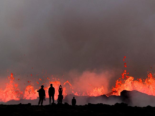 Fire in the hole: People watch lava during a volcanic eruption near Litli Hrutur, southwest of Reykjavik, Iceland. Picture: Kristinn Magnusson / AFP