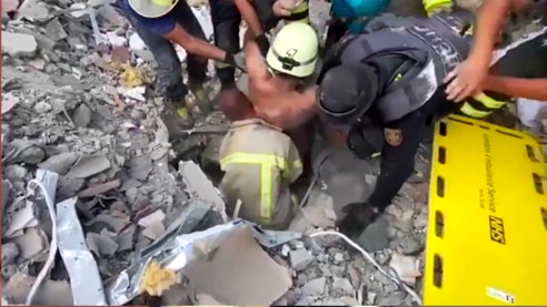 Emergency workers free the man trapped under the rubble.