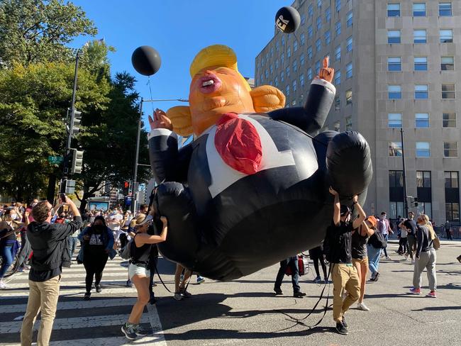 People carry a Trump inflatable as they celebrate on Black Lives Matter plaza across from the White House in Washington, DC after Biden’s win. Picture: AFP