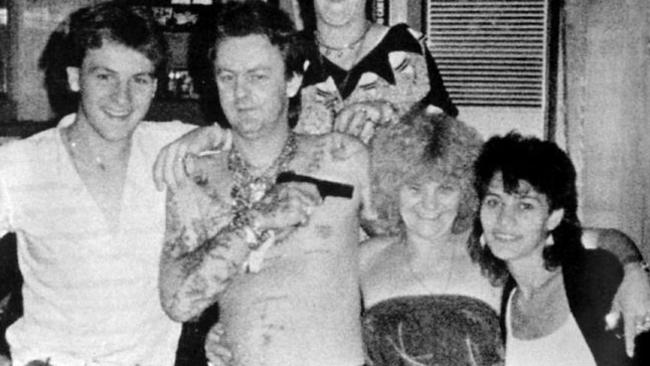 Dennis Allen playfully points a pistol at the head of his mother Kath Pettingill at a party in one of their Richmond houses.