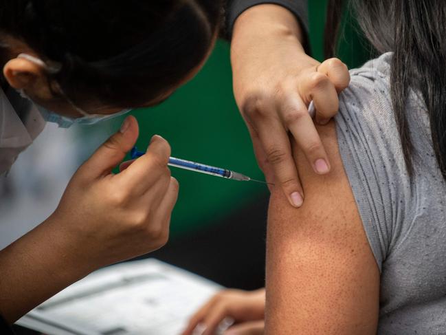 A nurse inoculates a woman with a booster dose of the AstraZeneca vaccine against COVID-19 in Mexico City, on February 9, 2022. (Photo by CLAUDIO CRUZ / AFP)