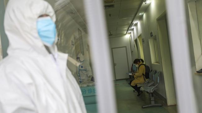 Medical workers in protective gear stand as a woman suspected of being ill with coronavirus waits to be seen at a community health station in Wuhan in central China's Hubei Province. (Chinatopix via AP)