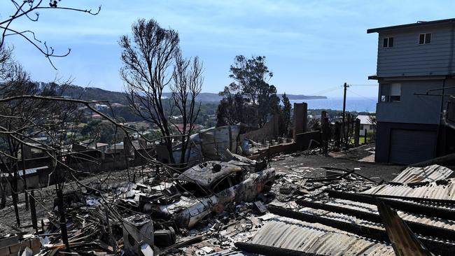 Some of the more than 70 houses and businesses destroyed by a bushfire in the coastal town of Tathra, Monday, March 19, 2018. RFS and NSW Fire and Rescue continue to mop up and douse smouldering homes after a devastating fire ripped through the community yesterday and overnight. (AAP Image/Dean Lewins) NO ARCHIVING