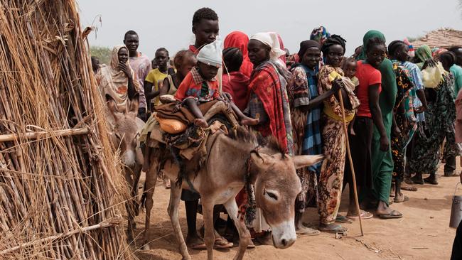 Ali Abdula, 16, guides his donkey carrying his two younger siblings, both suffering from malnutrition, past people lining up to register for aid at a camp for internally displaced persons (IDP) in Agari, South Kordofan in June. Picture: AFP