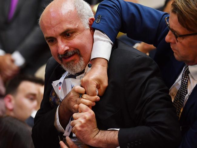 The protester held up a sign that read “nuclear weapons ban treaty” before being forcefully removed from the press conference. Picture: AFP/ Yuri Kadobnov.