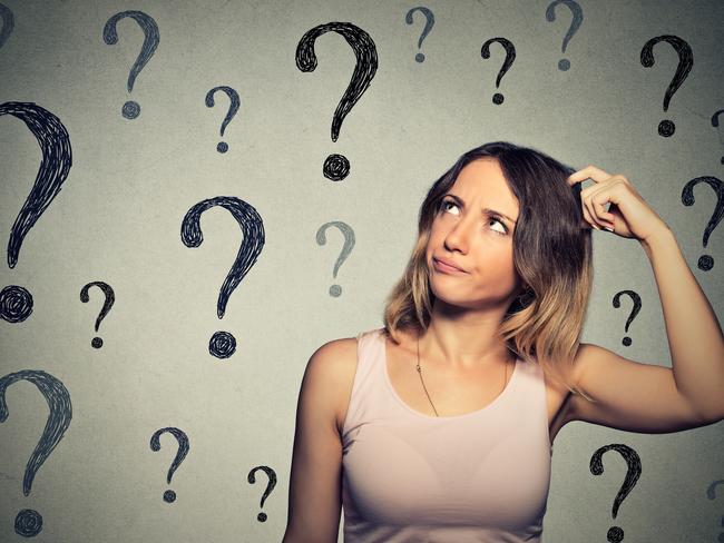 Thinking young woman looking up at many question marks isolated on gray wall background forgetting generic, forgetful