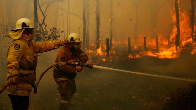 Battling an out-of-control fire near houses along Lemon Tree Passage Rd, in Salt Ash on Friday morning. Picture: AAP