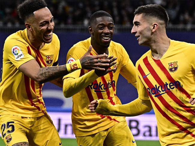 TOPSHOT - Barcelona's Spanish forward Ferran Torres (R) celebrates with Barcelona's Gabonese midfielder Pierre-Emerick Aubameyang (L) and Barcelona's French forward Ousmane Dembele (C) after scoring a goal during the Spanish League football match between Real Madrid CF and FC Barcelona at the Santiago Bernabeu stadium in Madrid on March 20, 2022. (Photo by JAVIER SORIANO / AFP)