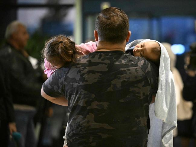 TOPSHOT - A man carries two children after arriving at Sofia airport on a Bulgarian government evacuation flight from Lebanon, in Sofia on September 30, 2024. (Photo by Nikolay DOYCHINOV / AFP)