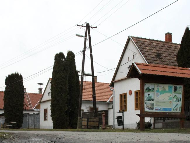 Houses are reflected in a puddle on the main road in the village of Megyer, Veszprem county, 190 kilometers (120 miles) southwest of Budapest, Hungary, Wednesday, Feb. 25, 2015. The village of Megyer, population 18, has put itself up for rent to companies and tourists. For 210,000 forints ($750; 690 euro) a day, a prospective renter gets seven guesthouses that sleep 39 people, four streets, a bus stop, a barn, a chicken yard, six horses, two cows, three sheep and four hectares (10 acres) of farmland - along with the possibility of temporarily being named deputy mayor. (AP Photo/MTI, Lajos Nagy)