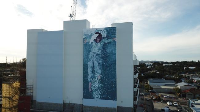 Logan artist Fintan Magee painted the massive 18m by 8m blue figure of a woman with her arms outstretched on to the south-facing wall of the York St building.