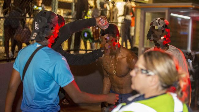 Youths douse themselves in water to ease the effects of the spray.