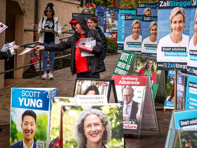 Volunteers hand out voting cards next to election candidate posters outside a pre-polling centre in Sydney. Picture: David Gray / AFP
