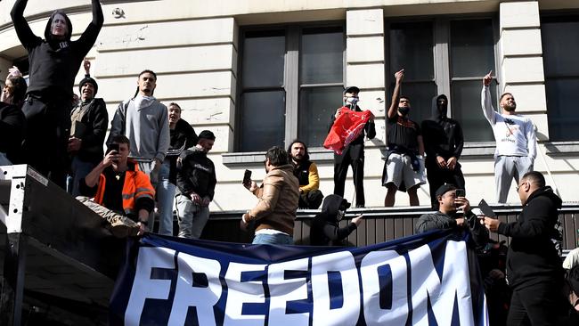 Protesters jump on a building roof, chanting and holding signs. Picture: Matrix