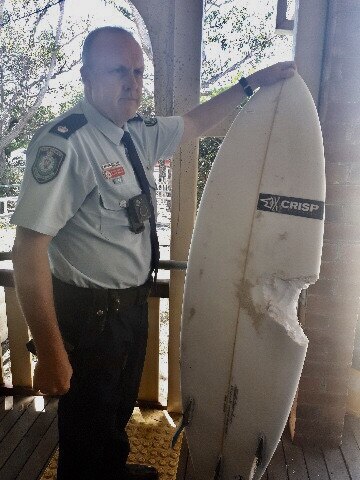 Matt Kehoe the Detective Inspector and Officer in Charge at Byron Bay Police Station with the surfboard of the shark attack victim. 