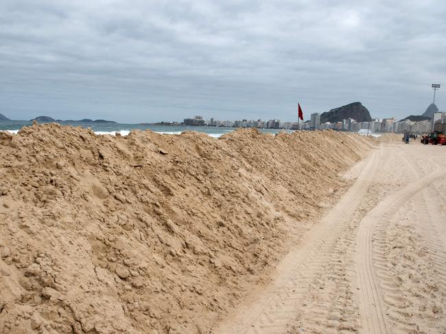 Workers make a sand barrier to protect the construction site of the Olympic beach volleyball stadium.