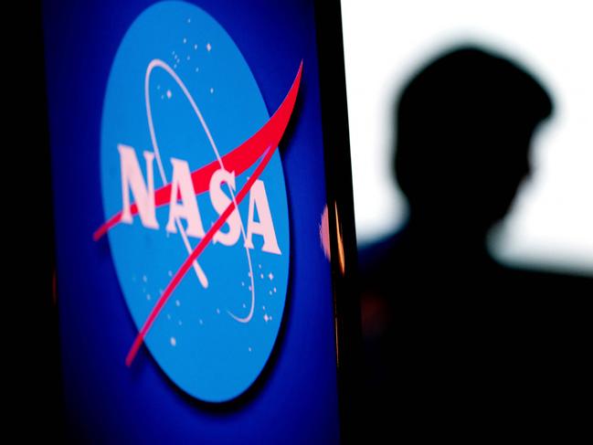 The silhouette of US engineer and NASA astronaut Megan McArthur is seen past the NASA logo in the Webb Auditorium at NASA headquarters in Washington, DC, on June 7, 2022. (Photo by Stefani Reynolds / AFP)