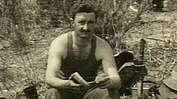 Korea, c. 1950-10. Wearing a singlet, 2/949 Corporal G.F. ('Fibber') McGee, a member of the Machine Gun Platoon, 3rd Battalion, The Royal Australian Regiment (3RAR), sits on the edge of a narrow slit trench or dugout and reads a book. Lying on the ground beside him (left) are a trenching tool, some ration boxes, a mug and a billy, while on the other side are some pouches, a slouch hat, a dixie and a pair of binoculars hanging from the barrel of his .303 rifle which is standing in the trench. At rear, some other soldiers are taking food out of ration boxes.   Picture: Australian War Memorial