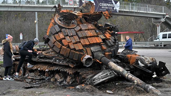 Residents look at a destroyed Russian tank on the outskirts of Buzova village, west of Kyiv, on April 10.