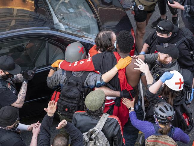 An injured man is taken away from the scene after a gunman drove toward protesters in Seattle. Picture: Dean Rutz/The Seattle Times via AP