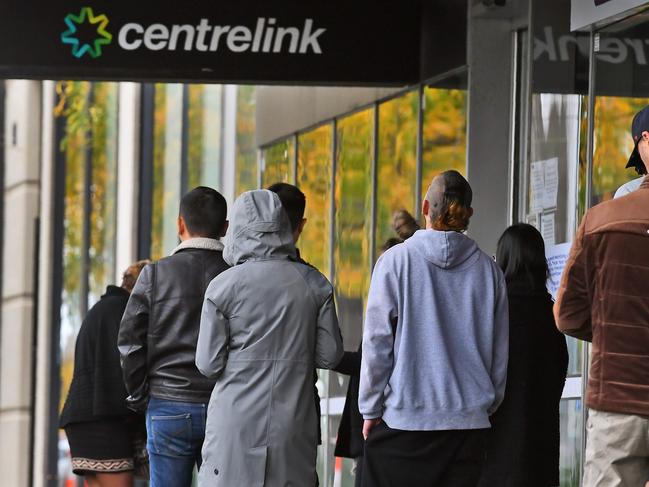 People queue up outside a Centrelink office in Melbourne on April 20, 2020, which delivers a range of government payments and services for retirees, the unemployed, families, carers and parents amongst others. - A report from the Grattan Institute predicts between 14 and 26 per cent of Australian workers could be out of work as a direct result of the coronavirus shutdown, and the crisis will have an enduring impact on jobs and the economy for years to come. (Photo by William WEST / AFP)