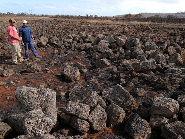 Fred Saunders (left) and Danny Lovett examine the remains of an aboriginal stone house unearthed by a 2006 bushfire near Tyrendarra. Picture: News Corp Australia