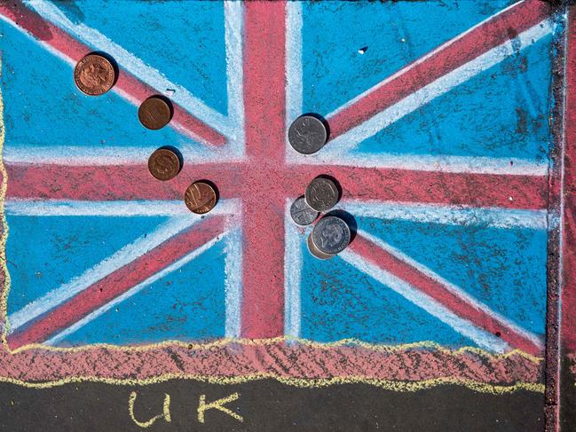 Pound sterling coins are pictured on a chalk drawing of a Union flag on the pavement in Trafalgar Square in central in London on March 7, 2017. Britain's Finance minister Philip Hammond earlier this week said he would keep chopping away at the deficit to get Britain fit to face Brexit, as he prepares to deliver his budget on March 8. / AFP PHOTO / CHRIS J RATCLIFFE