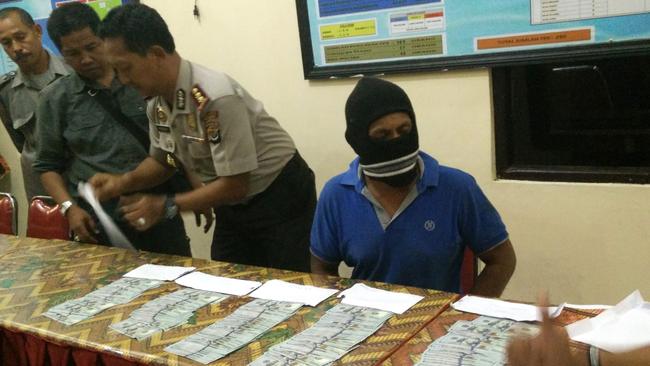 Indonesian police present an Indonesian crew member of a people-smuggling boat and money allegedly given to the crew by an Australian official to turn back.