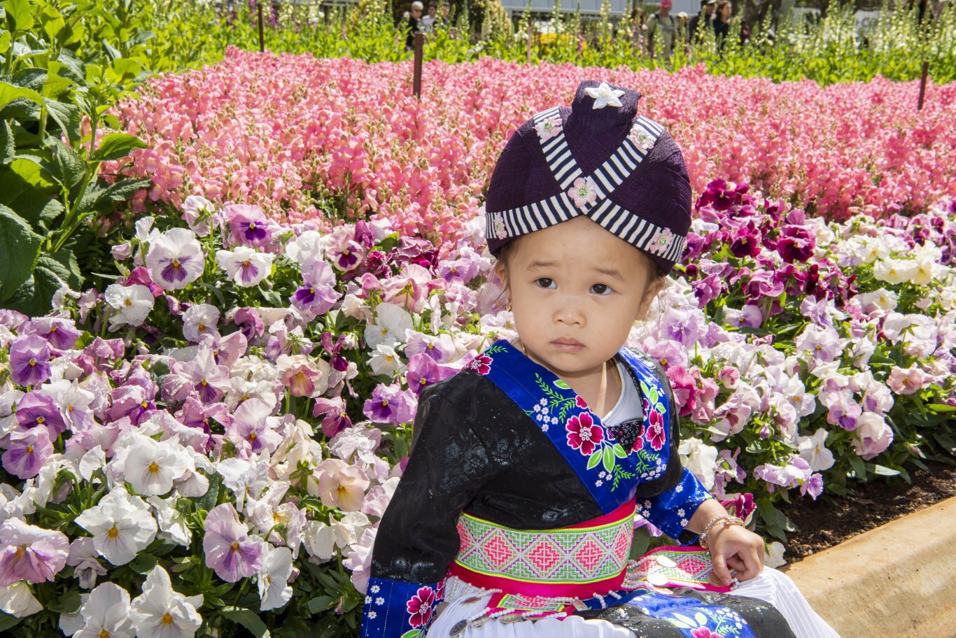 Two year old Chee Lee wears traditional Hmong dress at Queens park.