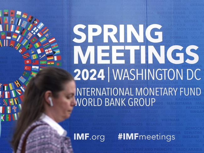 WASHINGTON, DC - APRIL 15: A woman passes by a sign during the annual Spring Meetings outside the IMF headquarters on April 15, 2024 in Washington, DC. The World Bank and IMF annual Spring Meetings are held from April 15 â 20, 2024 in Washington.   Alex Wong/Getty Images/AFP (Photo by ALEX WONG / GETTY IMAGES NORTH AMERICA / Getty Images via AFP)
